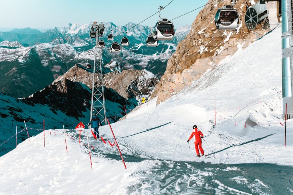 A skier descends a snowy slope at Zell am See with cable cars and majestic mountains in the background.